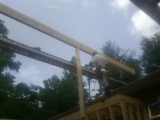 Carpenter setting a ridge beam over a new addition frame — Ice Dam Removal by Roofing Brothers in Canmer