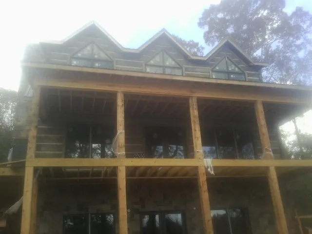 Dormers and porch framing on a large log home under construction — Roof Coating work by our crew in Canmer