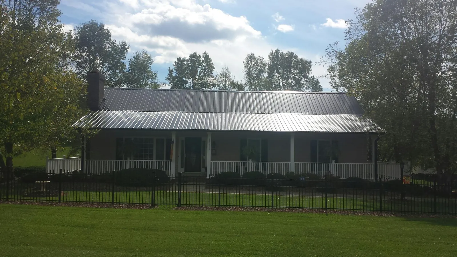 Gray metal roof on a brick ranch with a full width front porch — Gutter Guard Installation work by our crew in Canmer