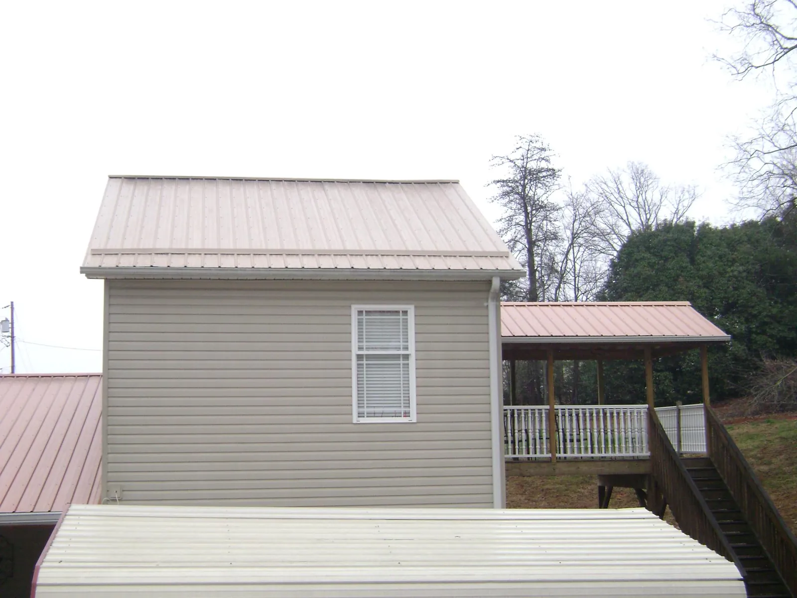 Tan metal roofs on a two story addition and attached porch, from a Roof Replacement job in Canmer