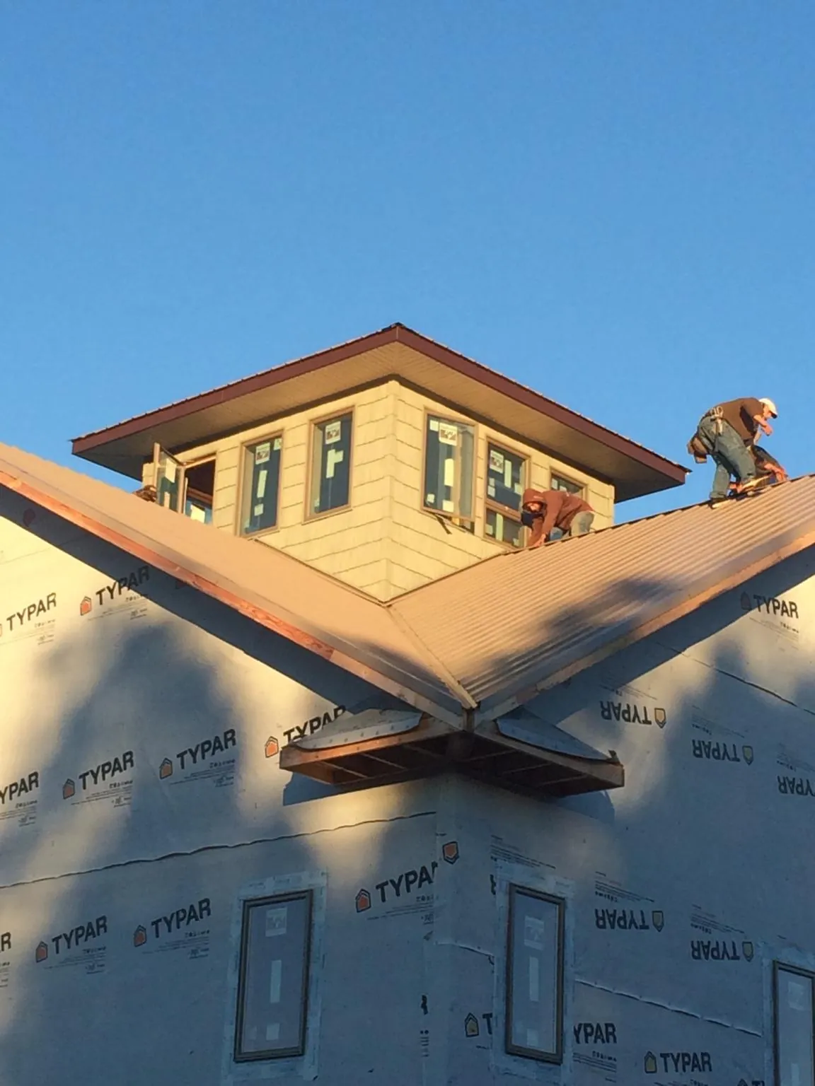 Roofers working around a rooftop cupola on a new metal roof at sunset — Roof Waterproofing in Canmer by Roofing Brothers